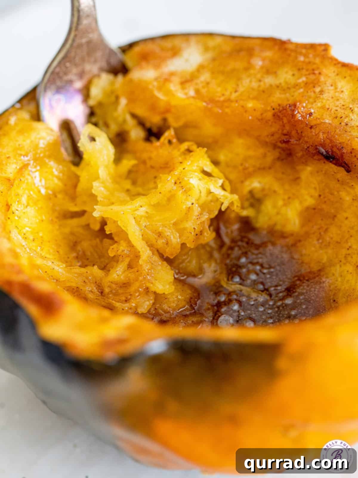 With just 4 ingredients, this Air Fryer Acorn Squash recipe turns squash into a flavorful, healthy side dish. Ready in just 30 minutes! A fork scooping out the inside of a perfectly cooked air fryer acorn squash, highlighting its tender and flavorful flesh.