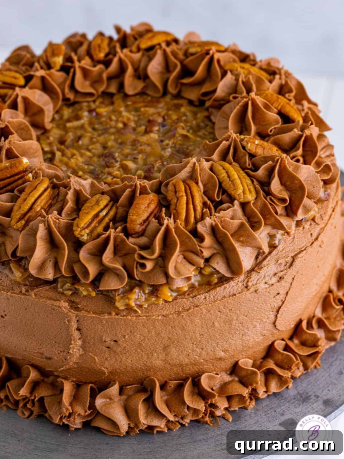 A perfect German Chocolate Cake with tender chocolate layers, coconut pecan frosting, and chocolate buttercream. Angled view of a completed German chocolate cake, showcasing its rich layers and decadent frosting.
