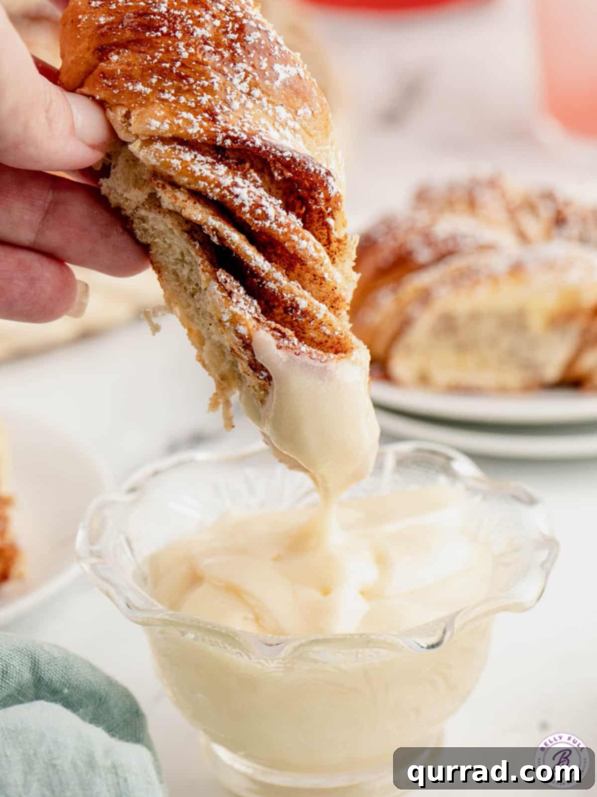 Enjoying Cinnamon Star Bread with a delicious side of cream cheese icing. A beautiful piece of cinnamon star bread being dipped into creamy cream cheese icing