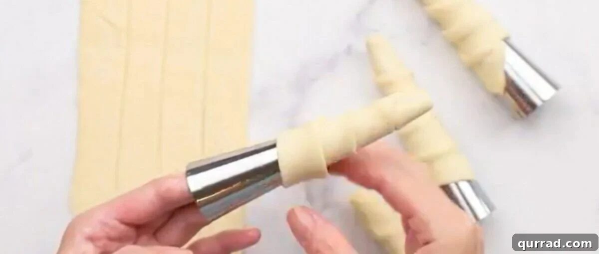Wrapping the pastry around the mold, demonstrating the overlapping technique for a perfect spiral.