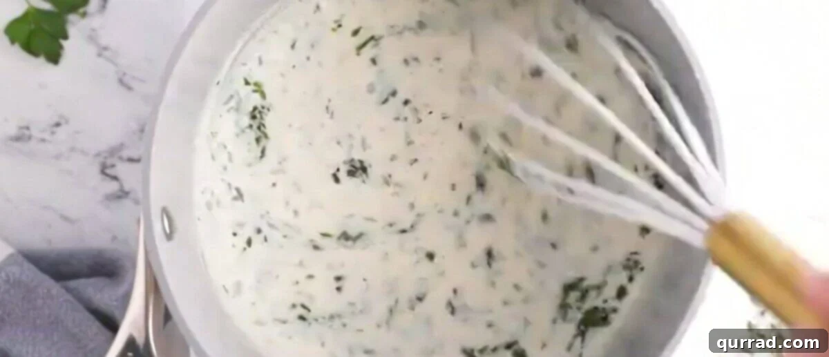 Rich & Creamy Potato Bake 3 Whisking the roux in a saucepan for the cheese sauce.