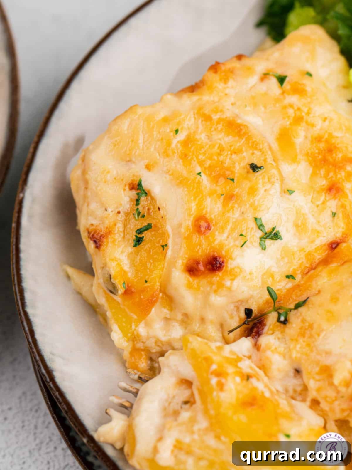 Easy Scalloped Potatoes: Cheesy, Creamy & Flavorful A serving of scalloped potatoes on a white plate, showing the creamy texture and melted cheese.