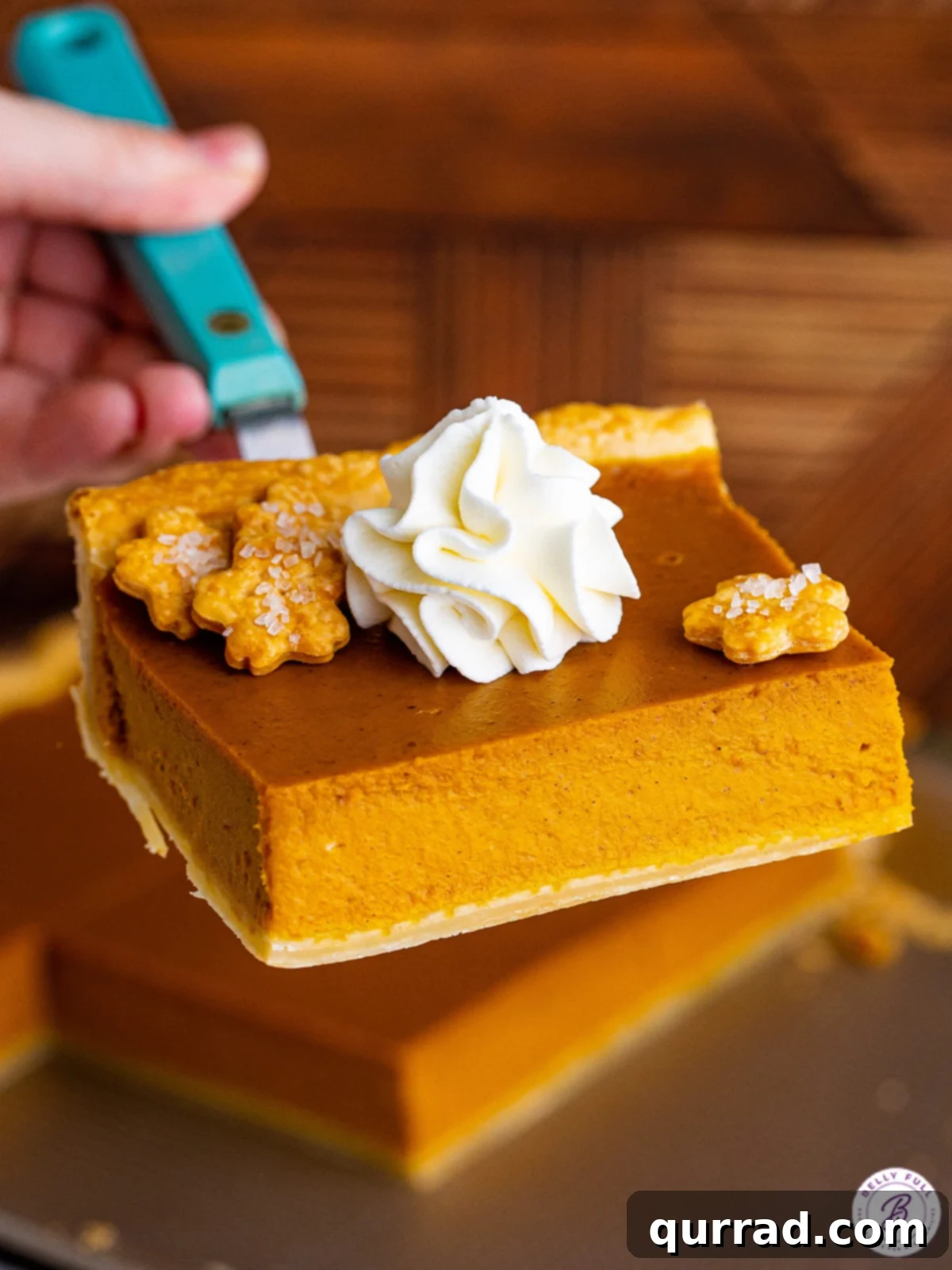 Discover the simplicity of this Easy Pumpkin Slab Pie, a foolproof recipe with a luscious, smooth filling, ideal for any gathering. A perfectly golden square of Pumpkin Slab Pie being lifted from the pan with a serving spatula, ready to be enjoyed.