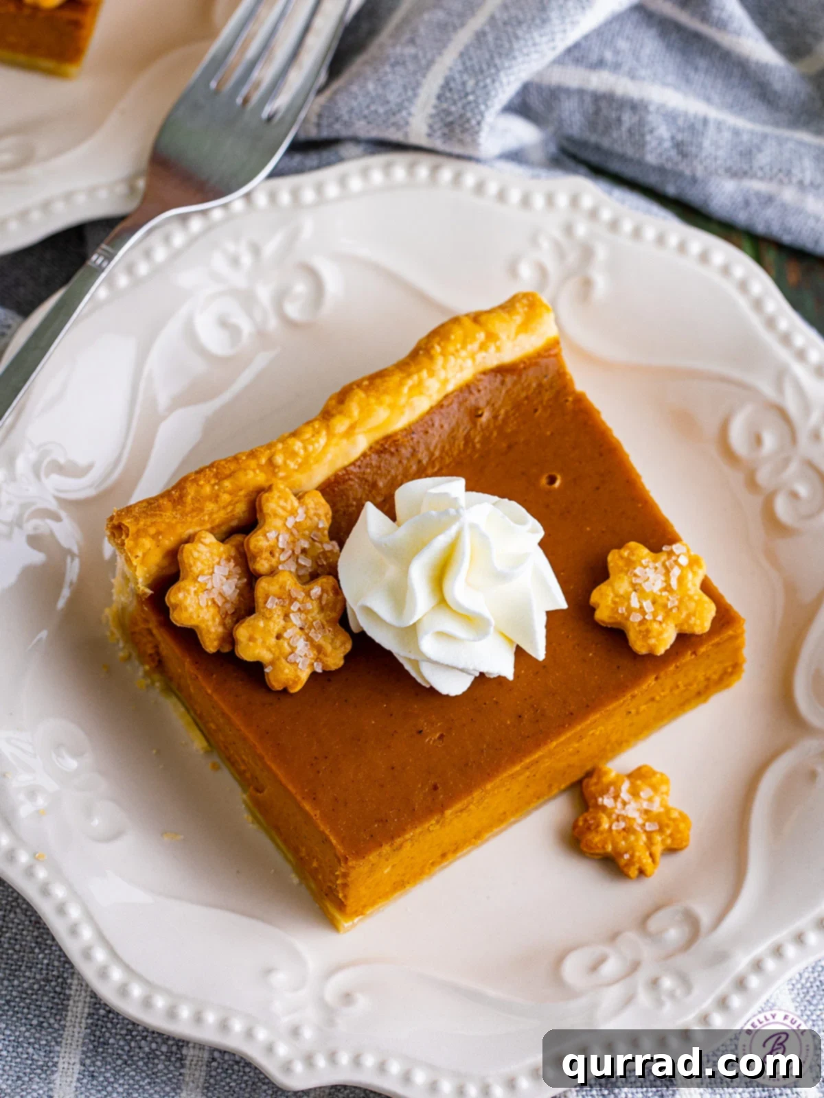 Enjoy a delectable slice of our easy Pumpkin Slab Pie, beautifully presented for a delightful dessert experience. A close-up, overhead view of a perfect square slice of pumpkin slab pie, invitingly placed on a simple white plate.