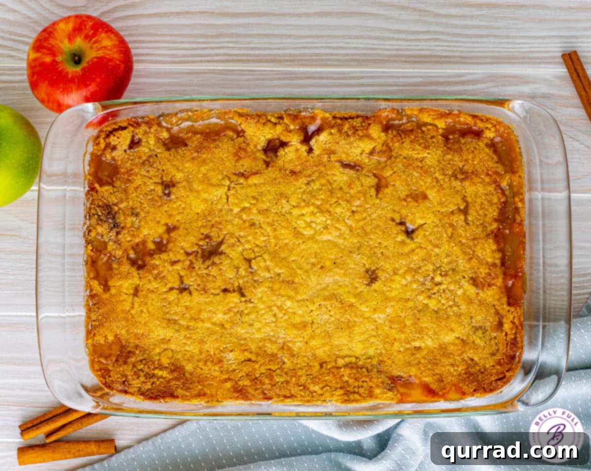 Irresistible Caramel Apple Dump Cake 8 A full glass casserole dish filled with a golden-brown, freshly baked caramel apple dump cake, ready to be served or stored.