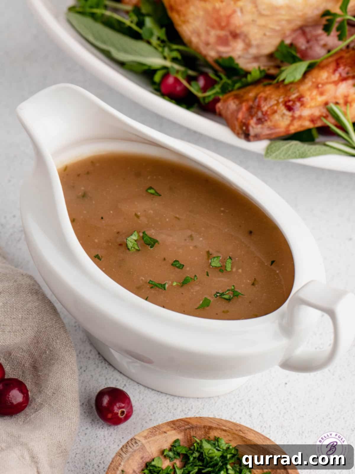 An overhead shot of a beautiful ceramic gravy boat filled with golden homemade turkey gravy, garnished with fresh herbs, ready for serving.