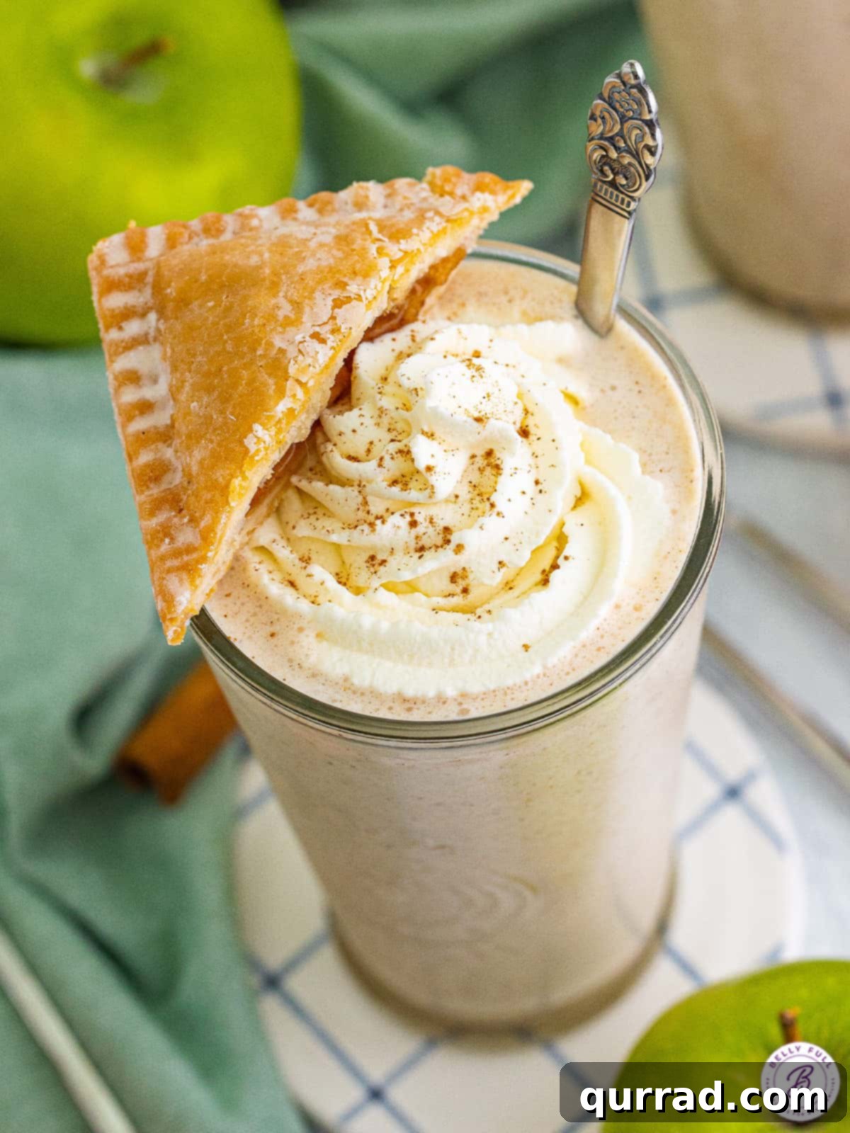 A close-up overhead view of a rich apple pie milkshake, adorned with whipped cream and a delicate piece of pie on top, ready to be enjoyed.
