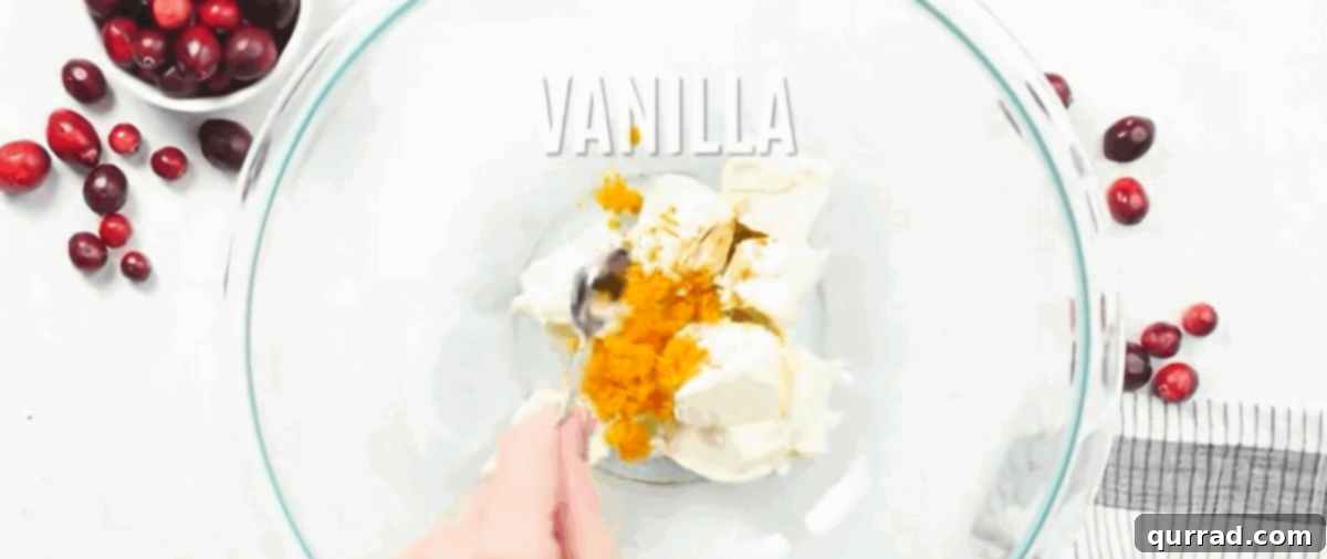Combining ingredients for the orange cream cheese topping in a glass bowl.