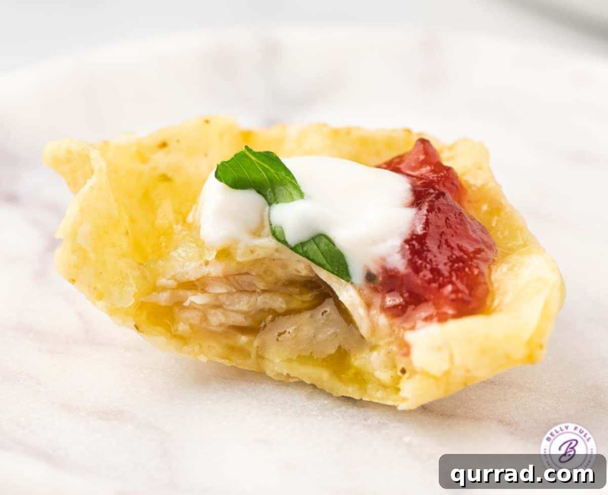 The perfect mix of Tex-Mex and Thanksgiving flavors in every bite, these Thanksgiving Nachos are a great way to use Thanksgiving leftovers. A single Thanksgiving nacho with a bite taken out, showcasing the layers of turkey, cheese, cranberry, and sour cream.