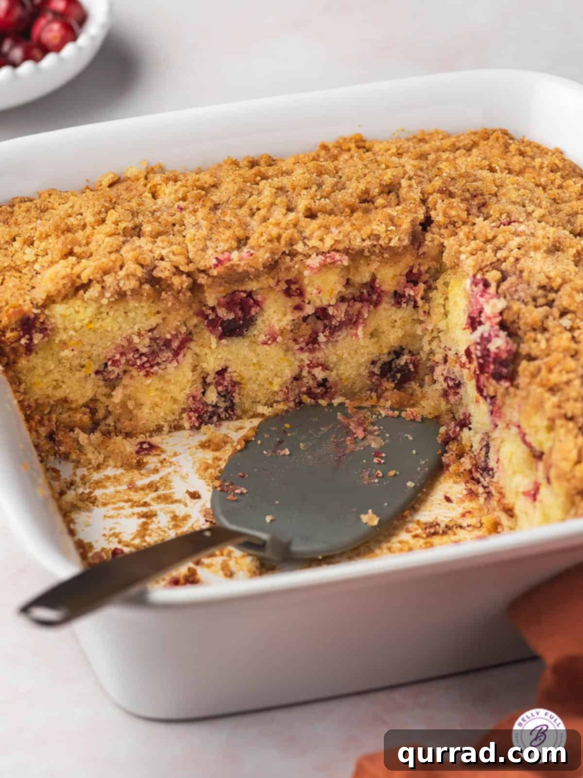 Sweet-Tart Cranberry Crumble Cake 4 sliced cranberry coffee cake in pan with serving spatula