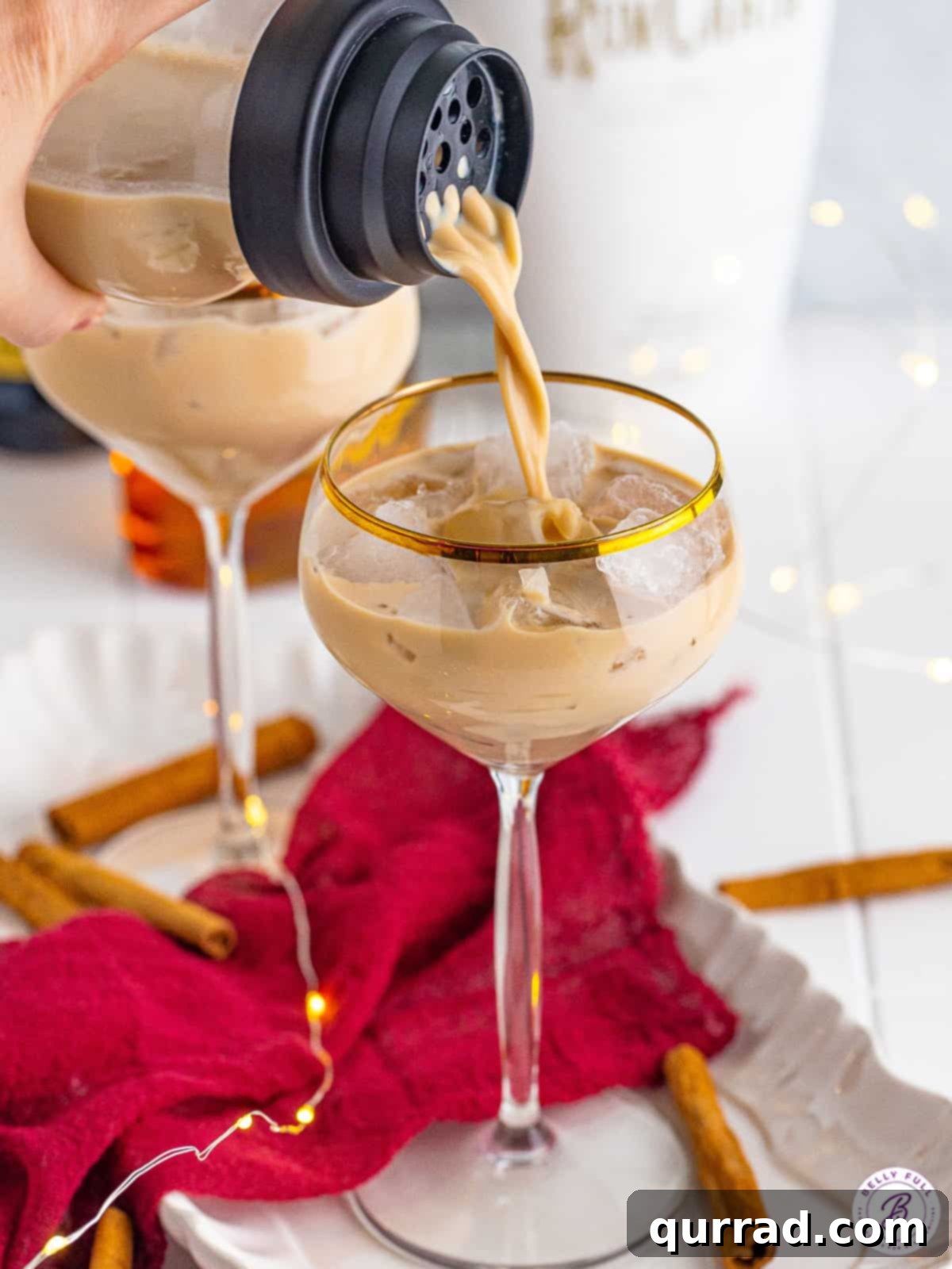 Cinnamon roll cocktail being poured into a glass with ice.