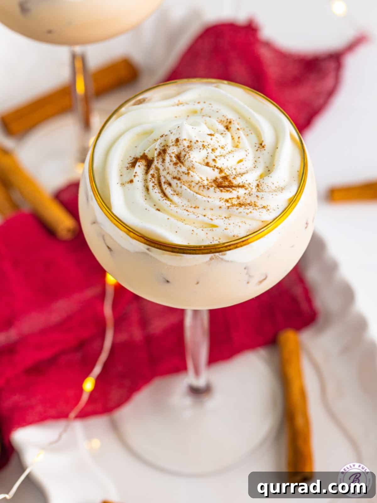 Angled overhead view of a cinnamon roll cocktail topped with whipped cream and cinnamon.