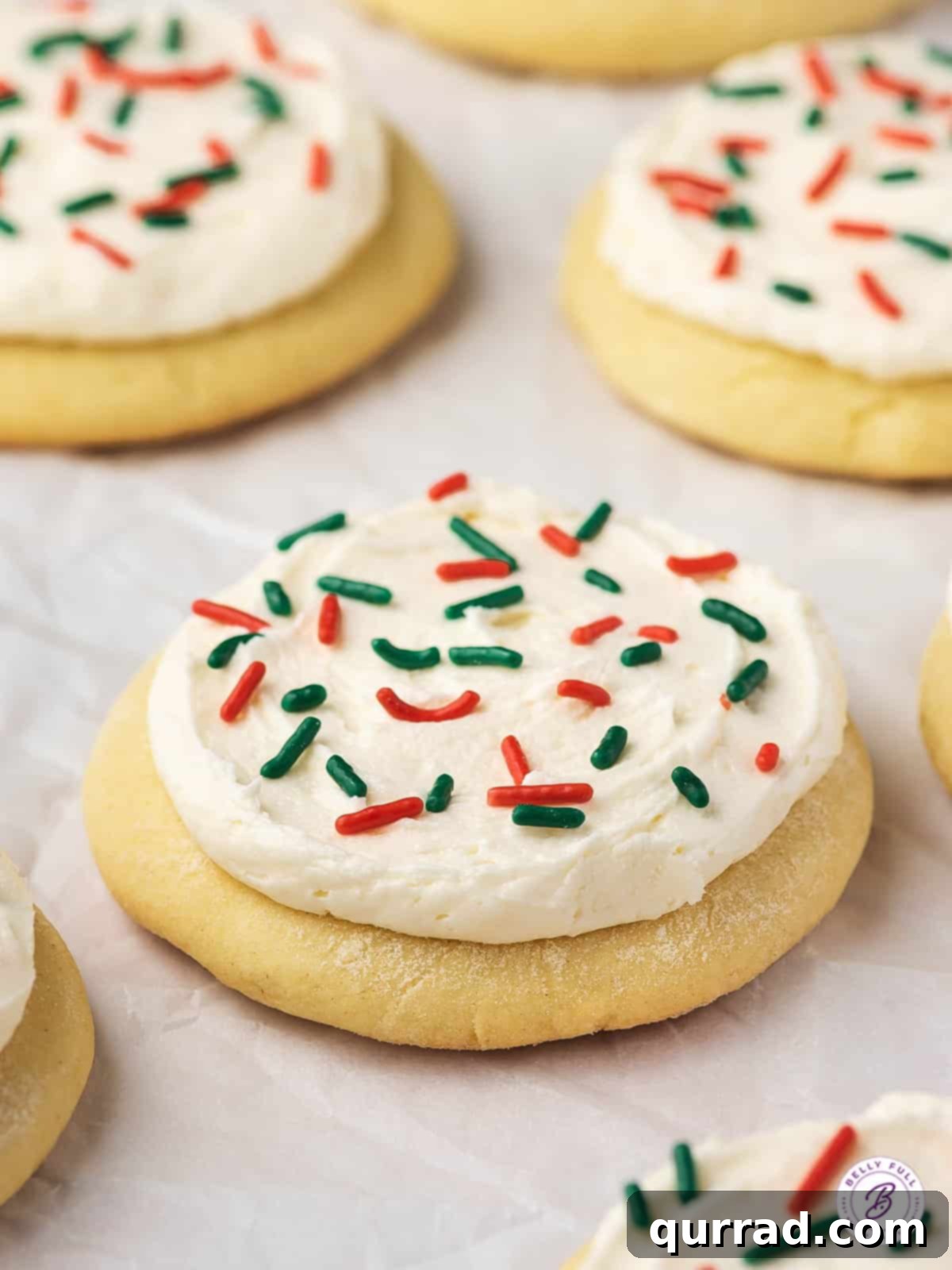 Lofthouse Inspired Soft Sugar Cookies 8 Lofthouse cookies with Christmas sprinkles on a white background, showcasing their thick frosting.