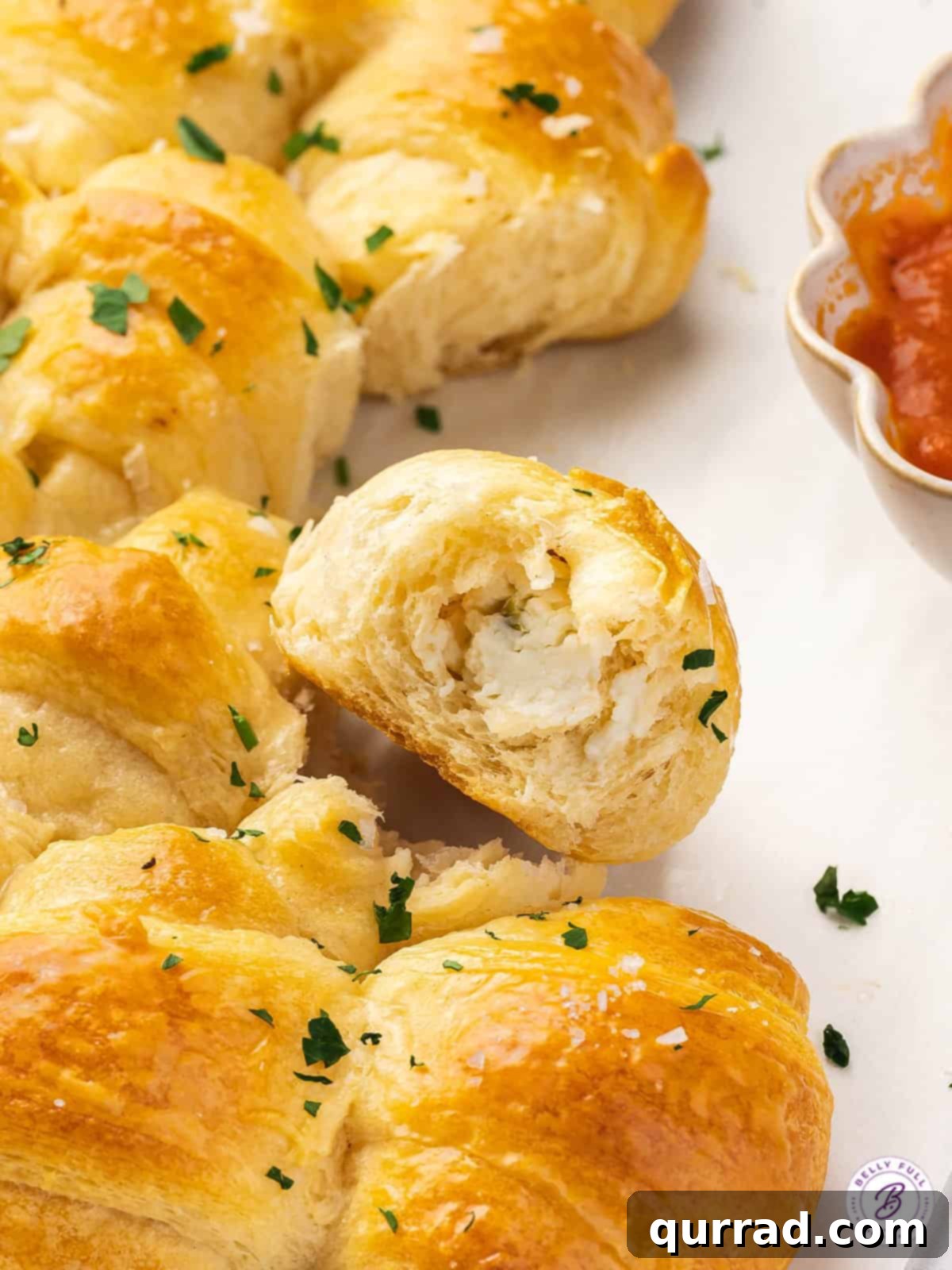 With flaky crescent rolls and herbed cream cheese, this Pull Apart Crescent Roll Christmas Tree is an easy holiday appetizer. Pieces of a crescent roll Christmas tree, one with a bite taken out of it, revealing the cheesy filling