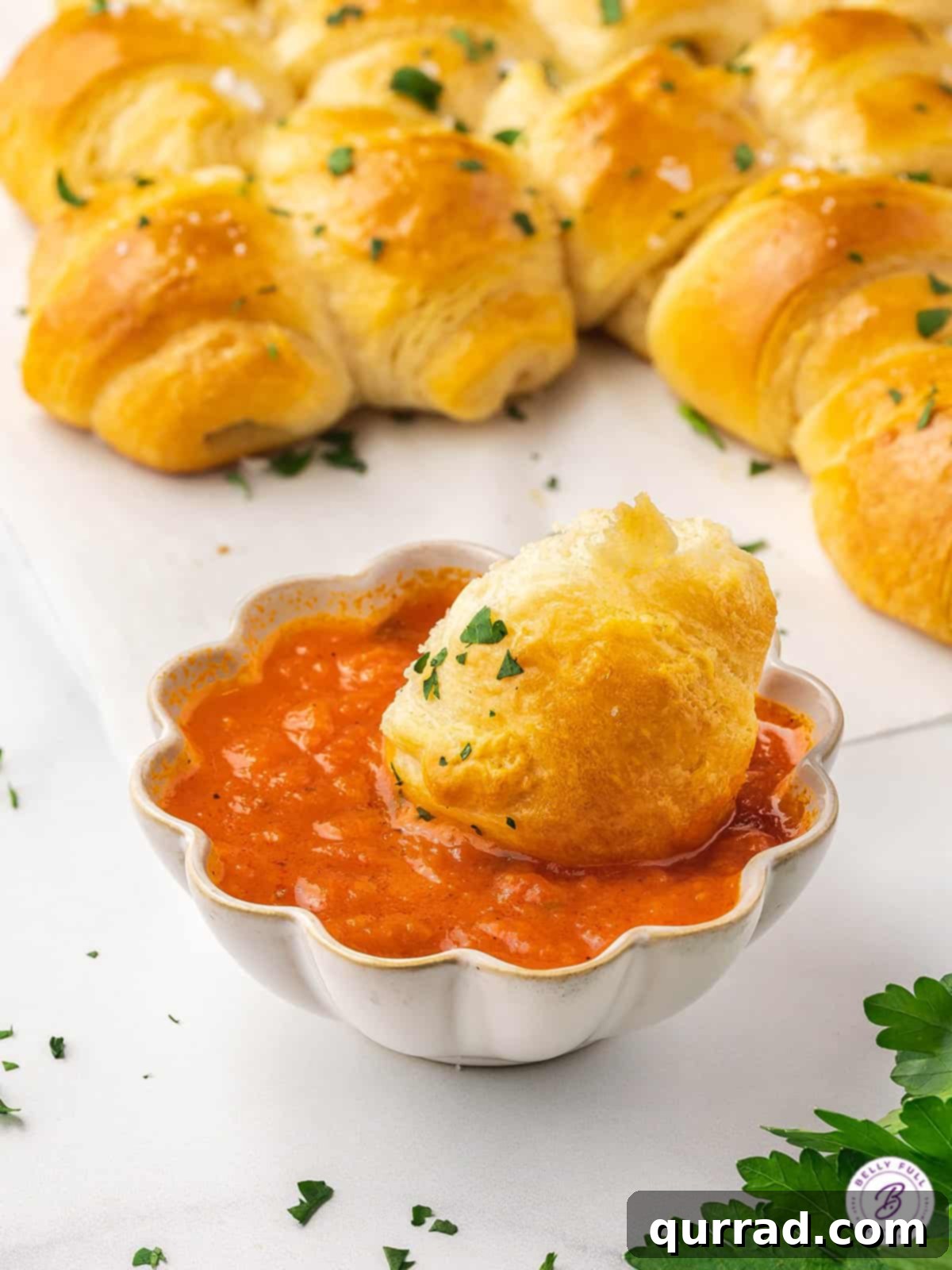 With flaky crescent rolls and herbed cream cheese, this Pull Apart Crescent Roll Christmas Tree is an easy holiday appetizer. A cheese filled crescent roll appetizer dipped in marinara sauce, showing the perfect texture