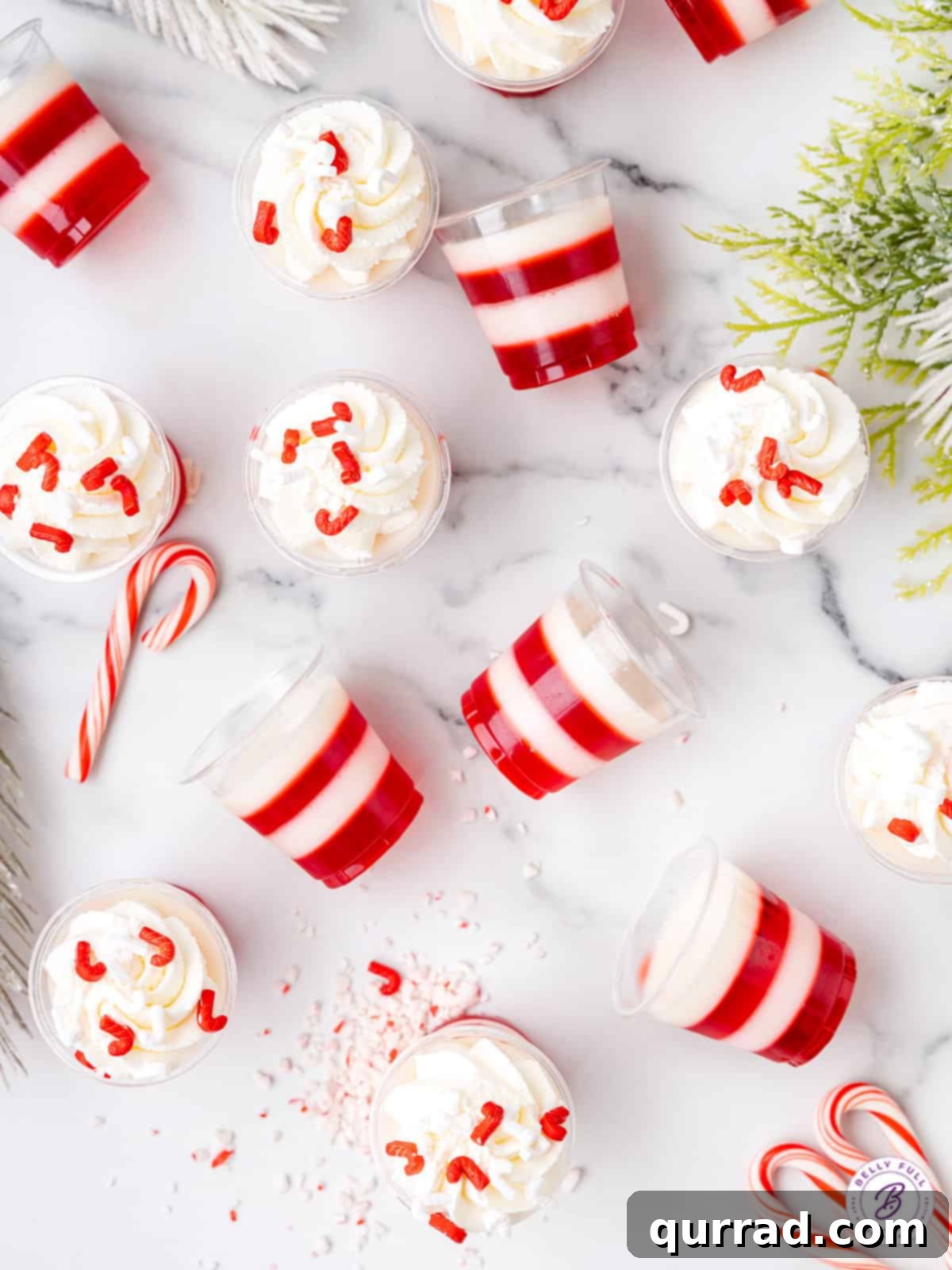 Peppermint Twist Shooters 4 Several perfectly crafted candy cane jello shots, showcasing their distinct red and white layers, resting on a marble countertop.