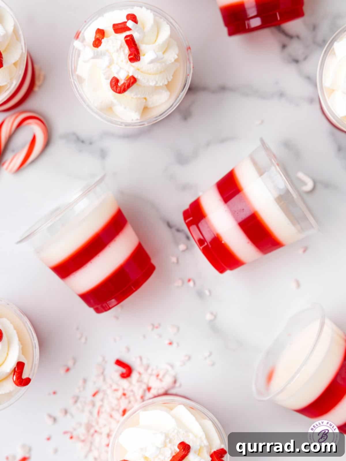 Peppermint Twist Shooters 5 A close-up view of several candy cane jello shots, artfully arranged on their sides to highlight the distinct and vibrant red and white layers.