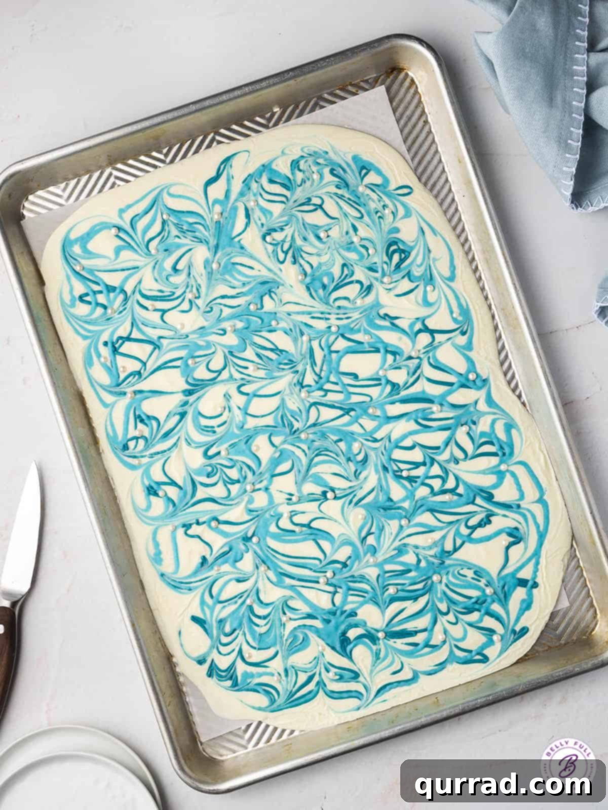 Overhead view of a white chocolate slab with elegant blue chocolate swirls, forming a beautiful Hanukkah bark pattern.