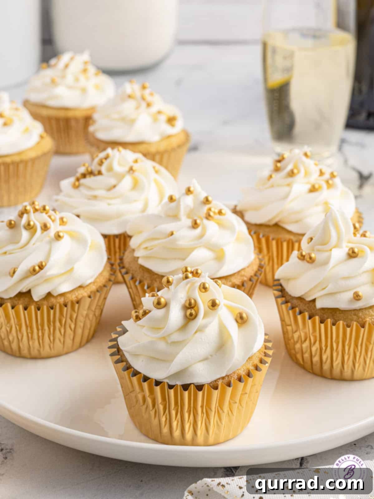 These moist, fluffy Prosecco Cupcakes are topped with a smooth buttercream frosting. An easy New Year's Eve dessert! Prosecco cupcakes on a white plate, showcasing their inviting presentation.