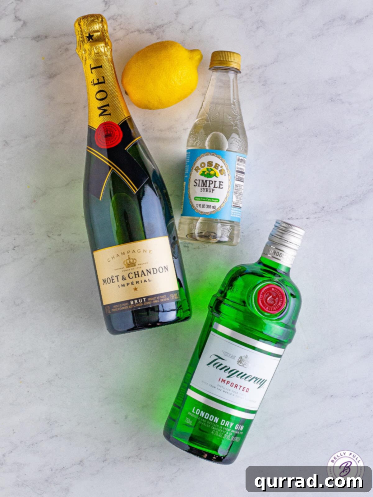 Made with gin, lemon juice, simple syrup, and champagne, this French 75 cocktail is easy to make and even easier to drink! A bottle of gin, a bottle of champagne, simple syrup, and a lemon on the counter