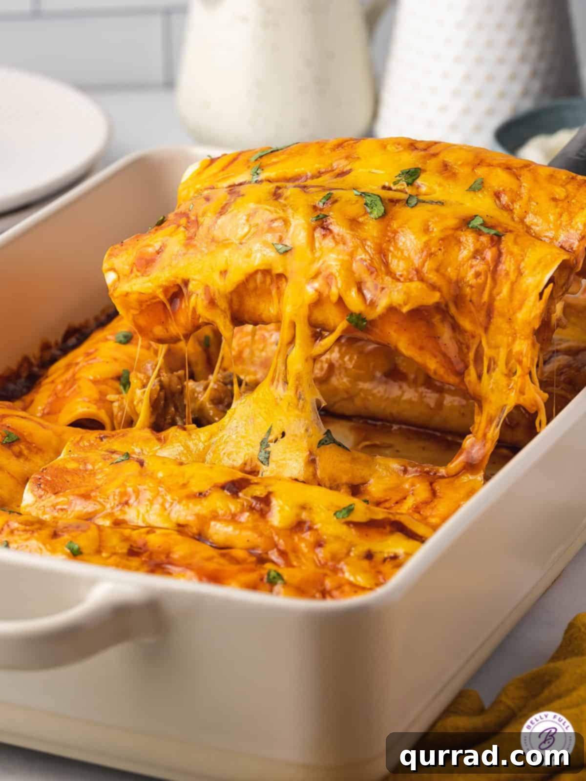 Two golden-brown enchiladas being lifted from a baking dish, showcasing melted cheese and a rich sauce.