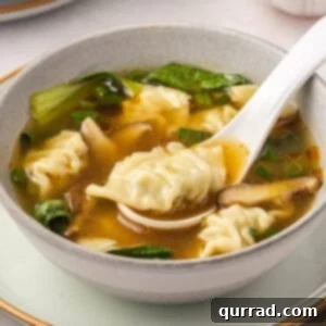 A bowl of homemade wonton soup with a white spoon