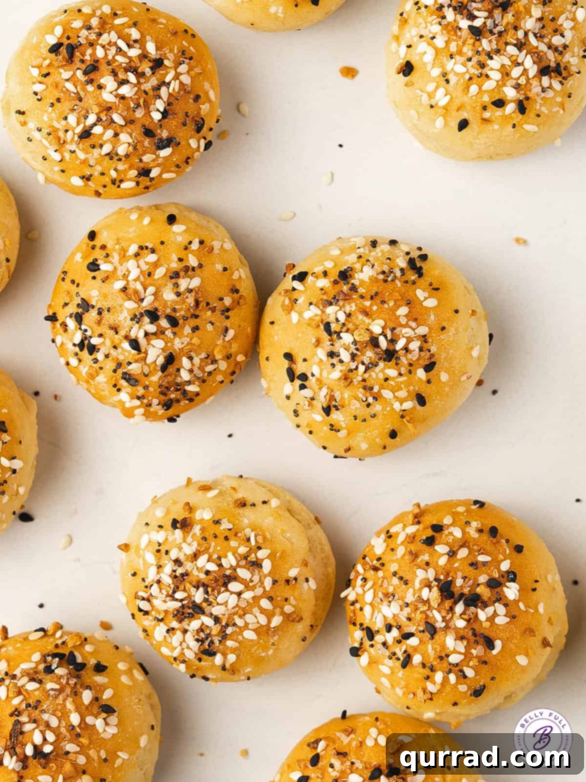 Delicious Air Fryer Bagel Minis with Everything Seasoning Overhead view of several perfectly golden everything seasoning bagel minis artfully arranged on a white plate, showcasing their texture and generous topping.