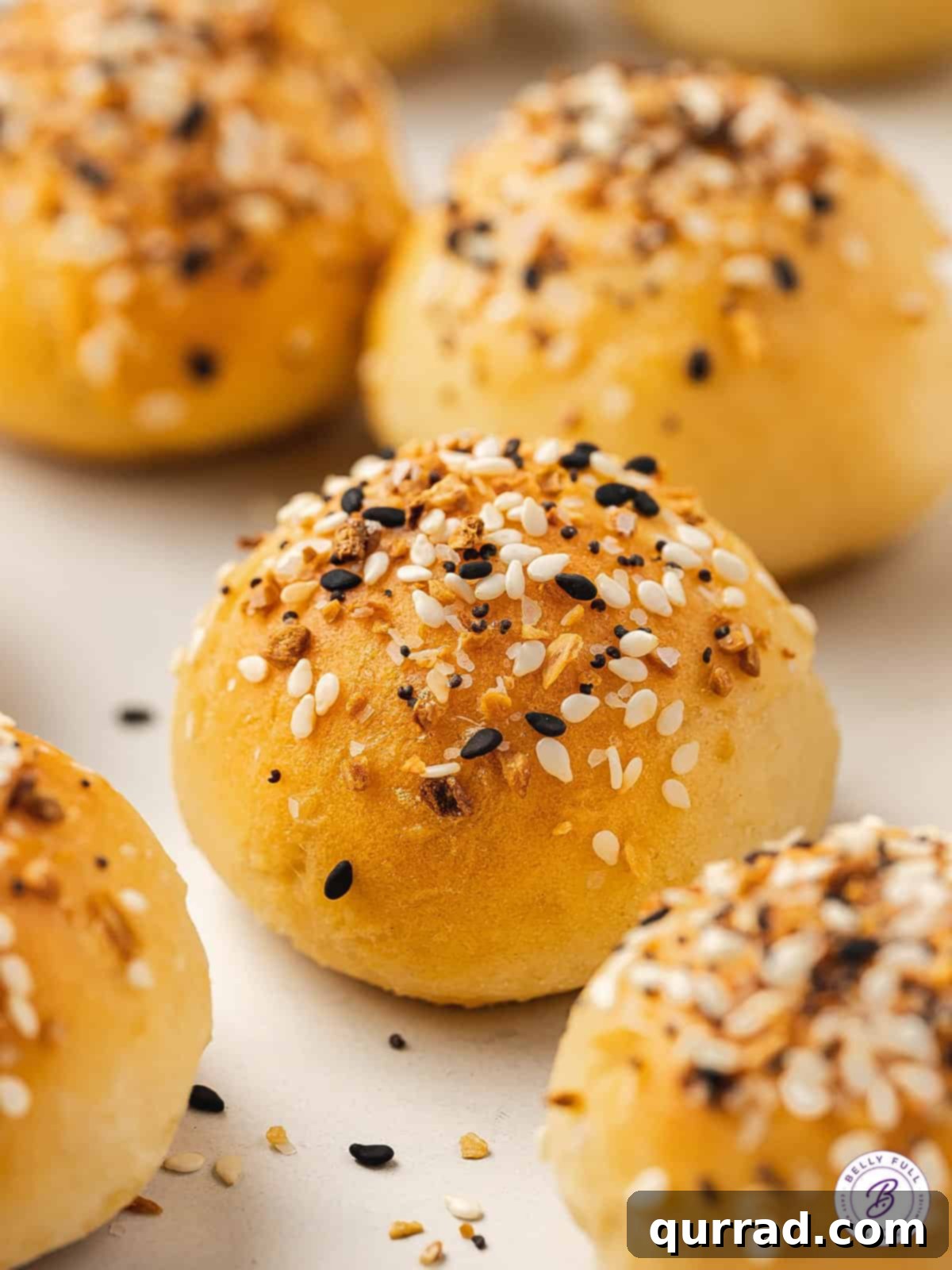 Delicious and Easy Air Fryer Bagel Minis Overhead view of several air fryer bagel bites, some with a bite taken out, resting on a white surface, showcasing their fluffy interior.