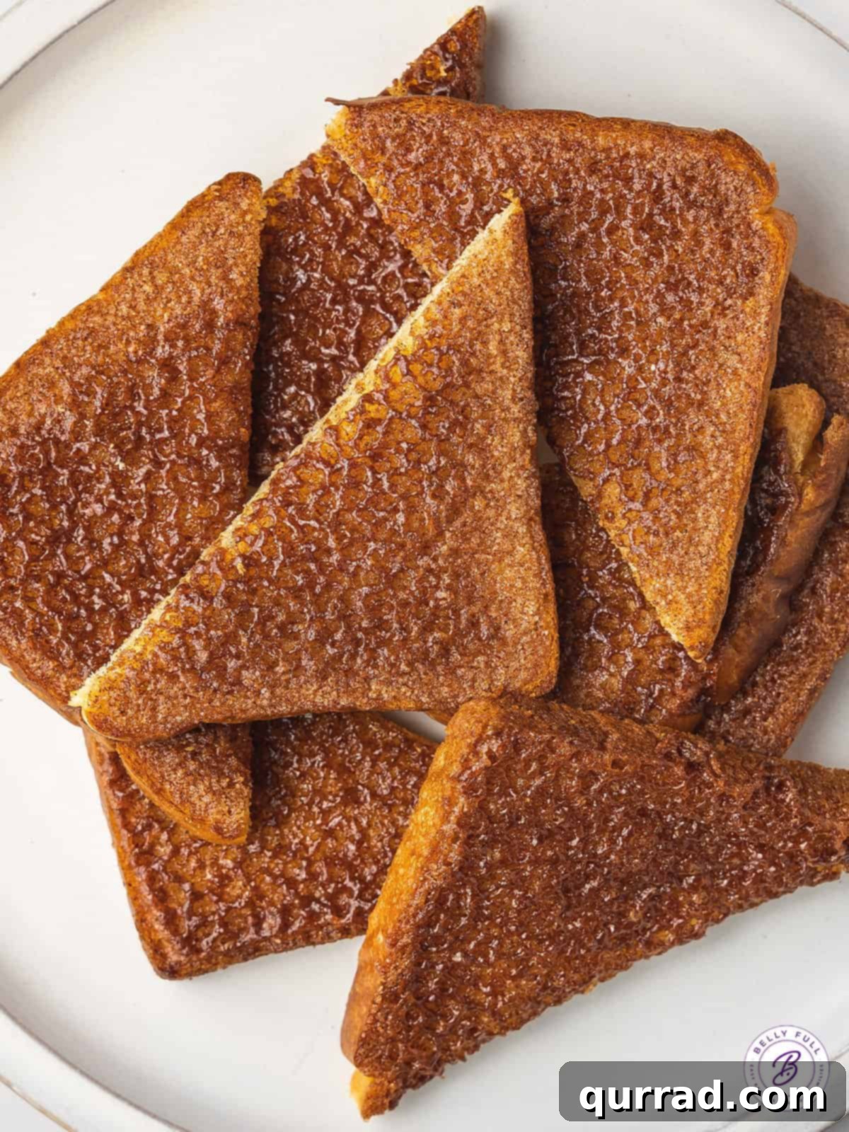 An overhead view of several slices of golden-brown cinnamon toast, ready to be enjoyed, highlighting the even distribution of the sugar-cinnamon topping.