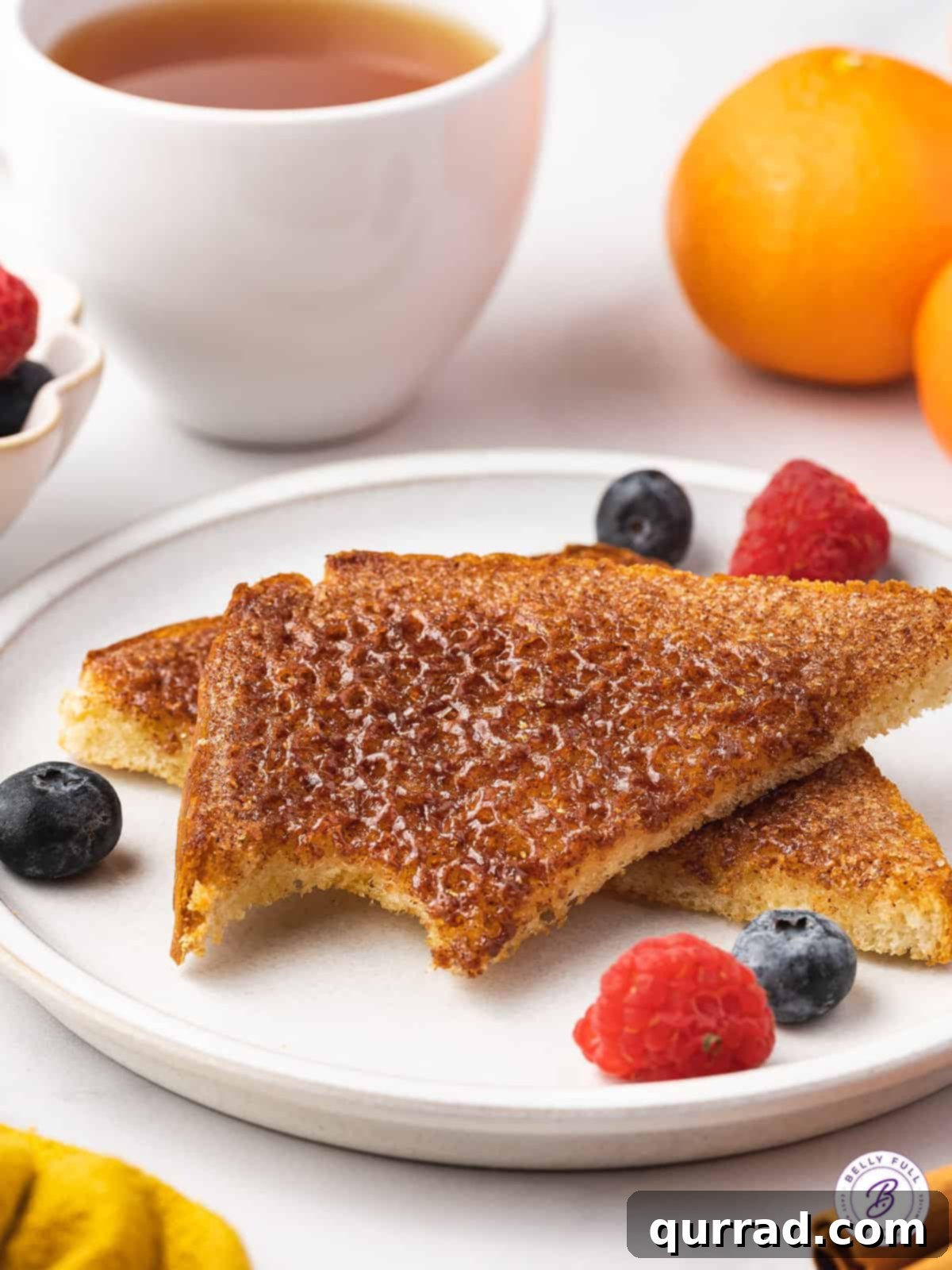 Two slices of golden-brown cinnamon toast on a plate, one with a delectable bite missing, invitingly revealing its soft interior and crispy topping.