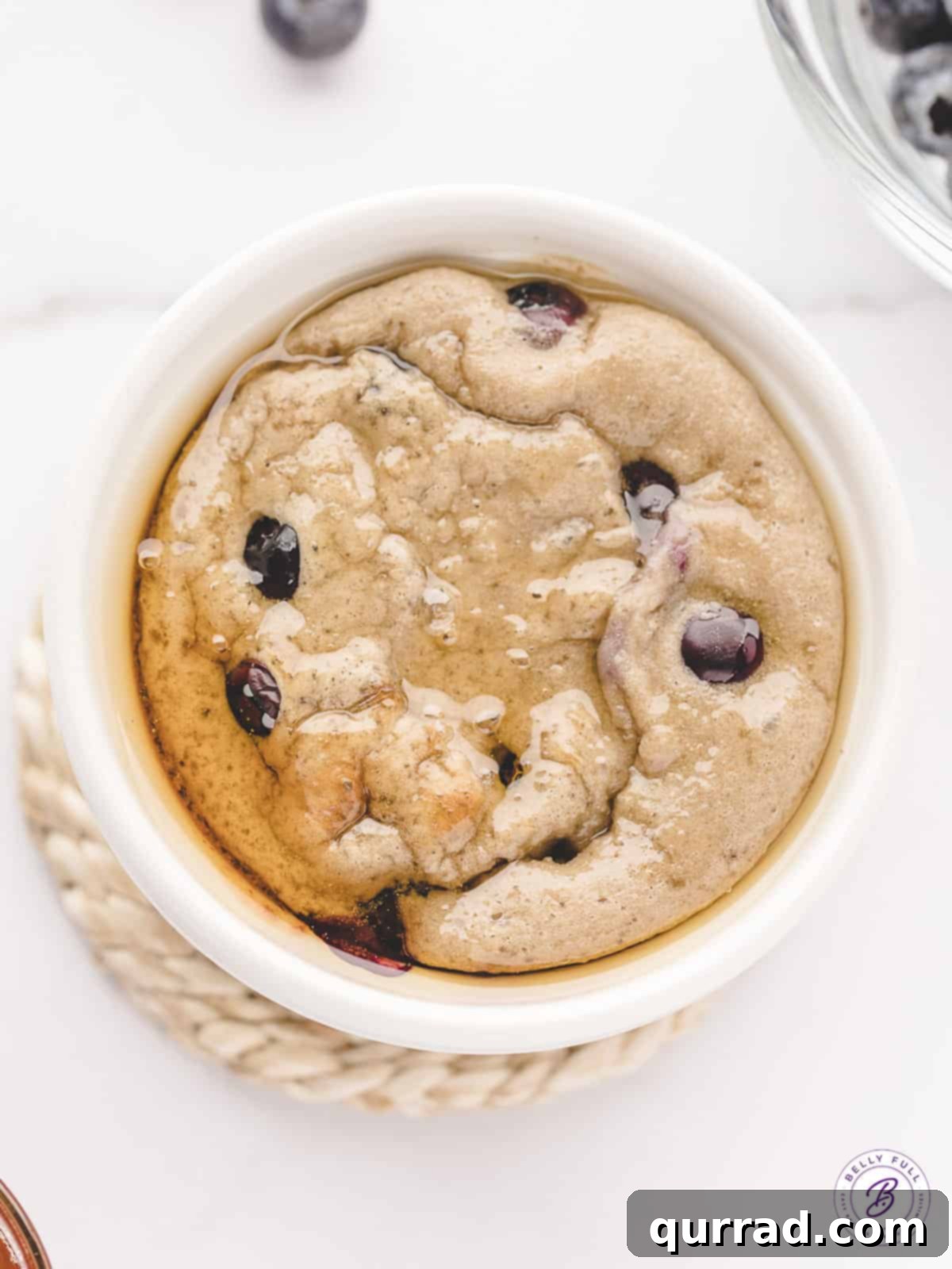 Blended Baked Oats: A perfect, single-serving breakfast. Overhead view of a single ramekin of blended baked oats, topped with fresh blueberries and a drizzle of maple syrup.