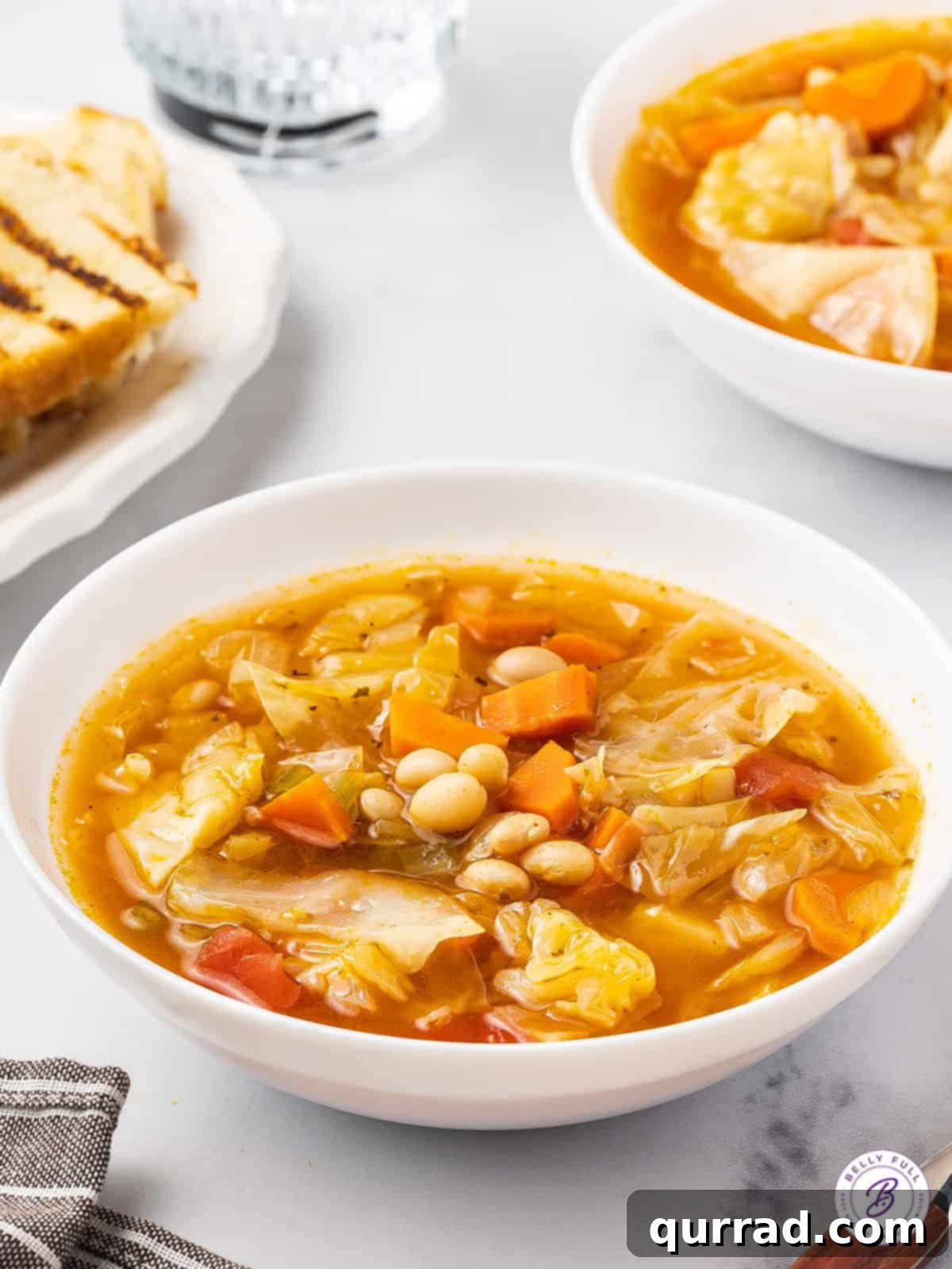 Easy & Healthy Cabbage Soup: A heartwarming blend of vegetables in a savory broth. An inviting angled view of a steaming bowl of healthy cabbage soup, garnished with fresh herbs, ready to be enjoyed.