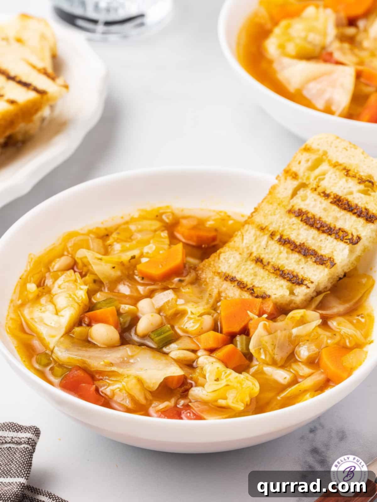 A comforting bowl of Cabbage Soup with crusty bread. A perfectly portioned bowl of healthy cabbage soup, served with a thick slice of crusty bread on the side, ready to be savored.