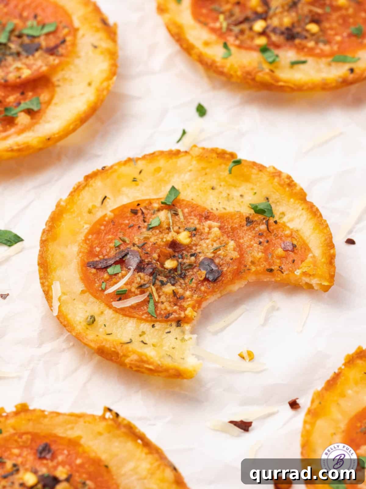 Enjoy a guilt-free bite of these flavorful Mozzarella Pizza Chips. A crispy mozzarella pizza chip with a bite taken out, showing its texture