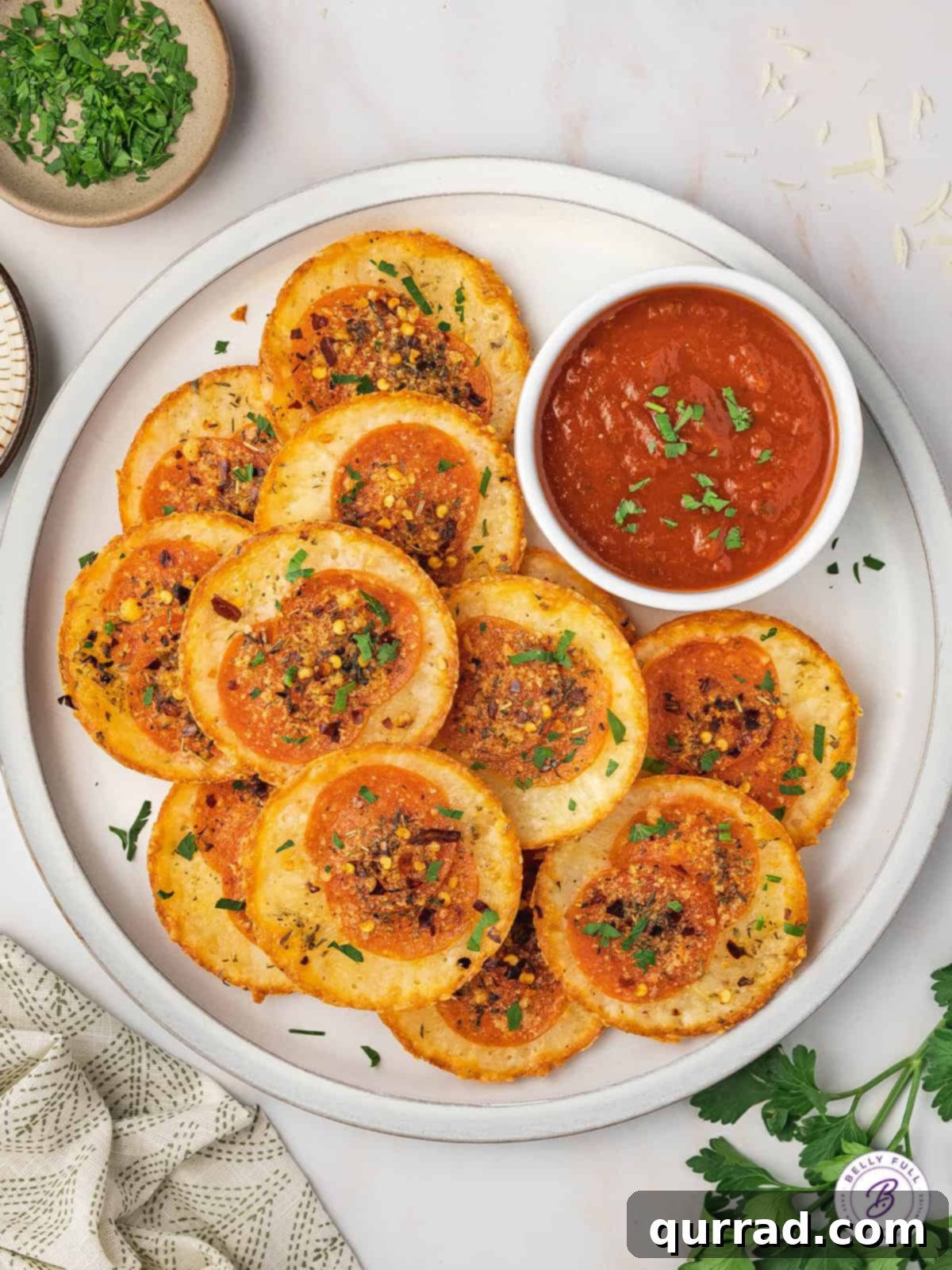 A perfect low-carb snack: Mozzarella Pizza Chips with marinara for dipping. Overhead view of a beautifully arranged plate of crispy pizza chips with a bowl of marinara sauce