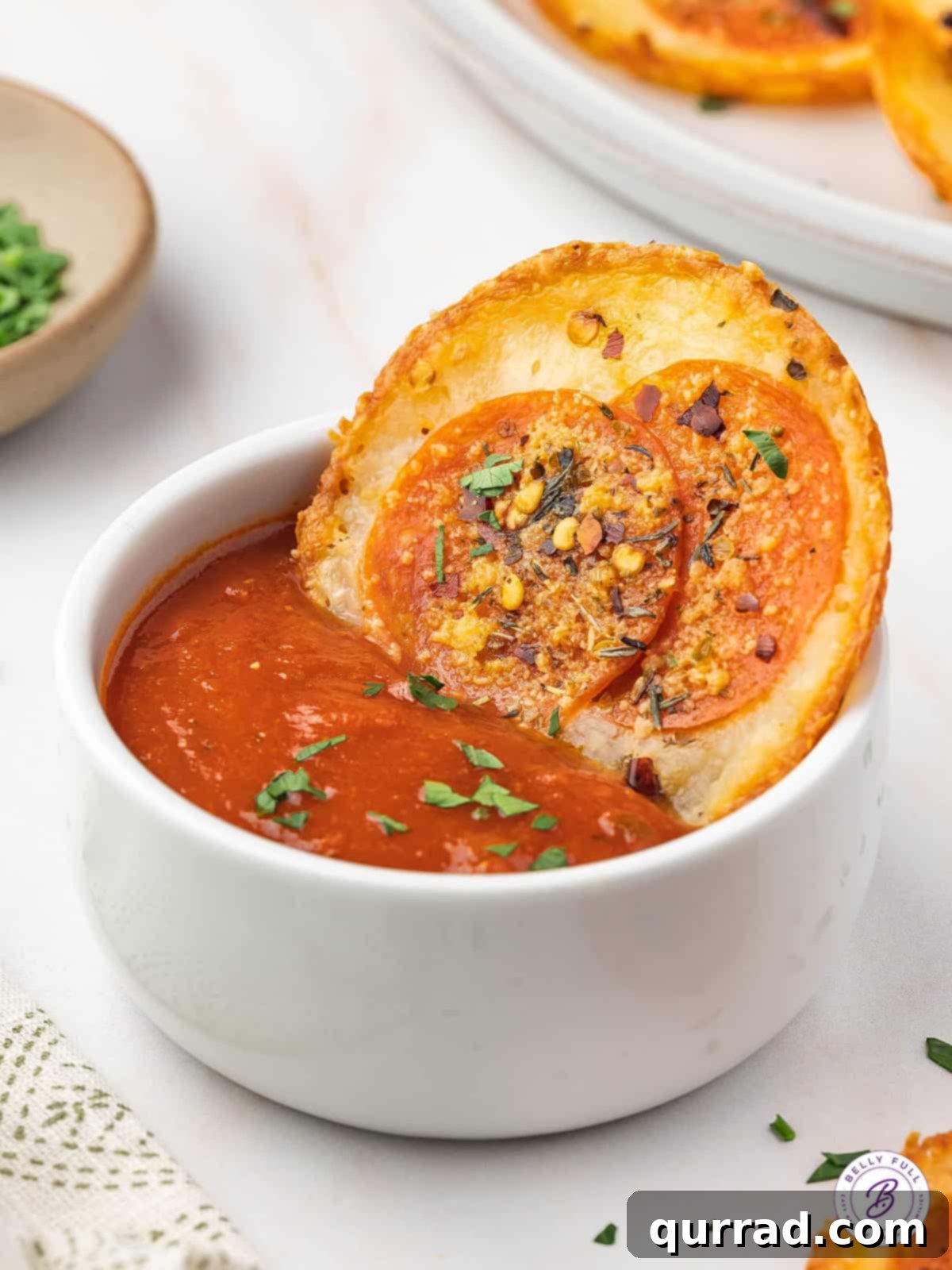 The ultimate low-carb indulgence: dipping a pepperoni pizza chip in marinara. A perfectly crispy pepperoni pizza chip being dipped into a rich marinara sauce