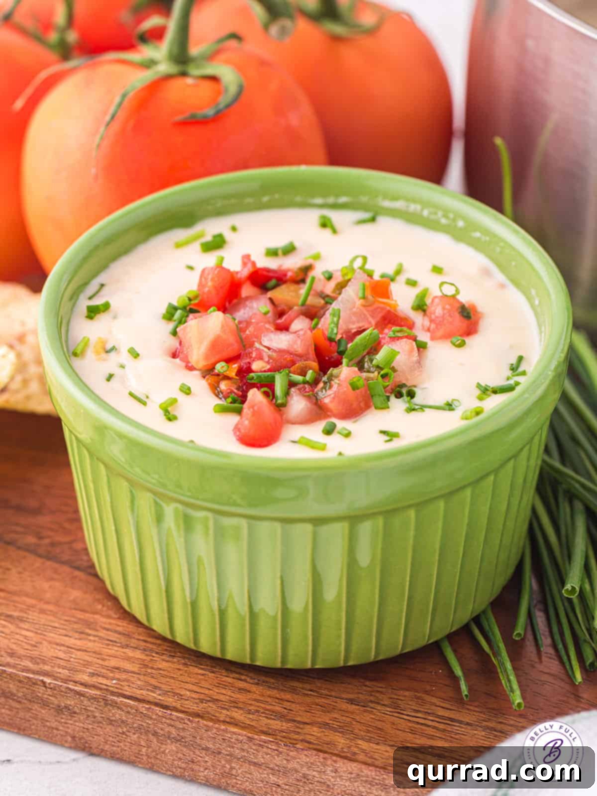 A vibrant green bowl filled with warm, creamy white queso dip, ready to be served with tortilla chips.