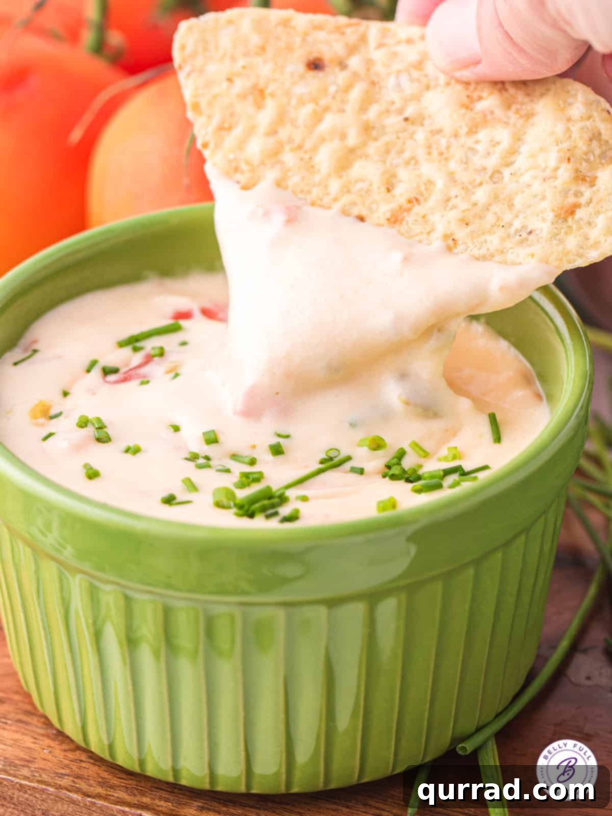 A crispy tortilla chip perfectly dipped into a rich and creamy Mexican cheese dip, ready to be enjoyed.