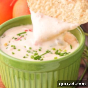 A tortilla chip dipped into Mexican cheese dip
