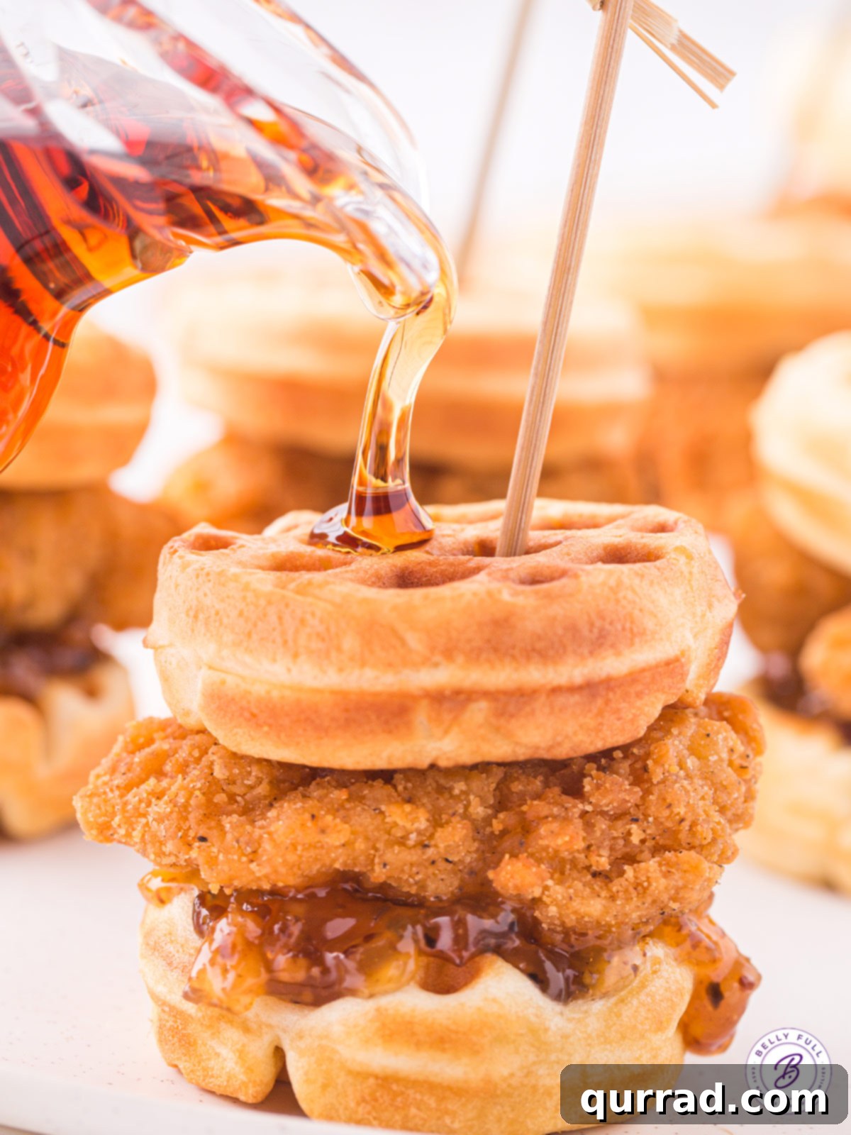 Sweet & Savory Bliss: Chicken and Waffle Sliders with Maple Syrup Drizzle. Golden maple syrup being drizzled over a stack of chicken and waffle sliders, emphasizing the sweet glaze.