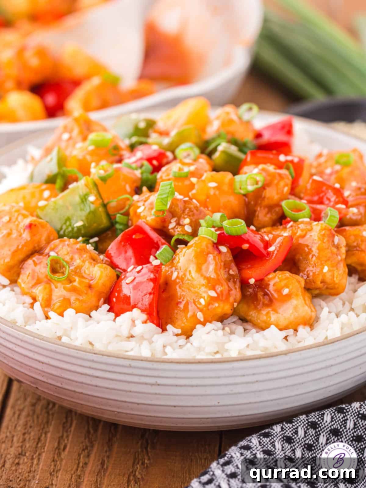 This easy homemade Sweet and Sour Pork recipe is a fantastic substitute for your favorite Chinese restaurant takeout. Sweet, sour, & savory! Angled view of sweet and sour pork over rice