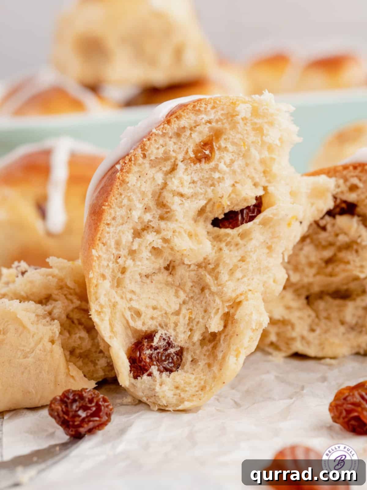These soft and fluffy Hot Cross Buns are filled with plump juicy raisins, brushed with an orange glaze, and topped with a icing cross. A hot cross bun broke in half