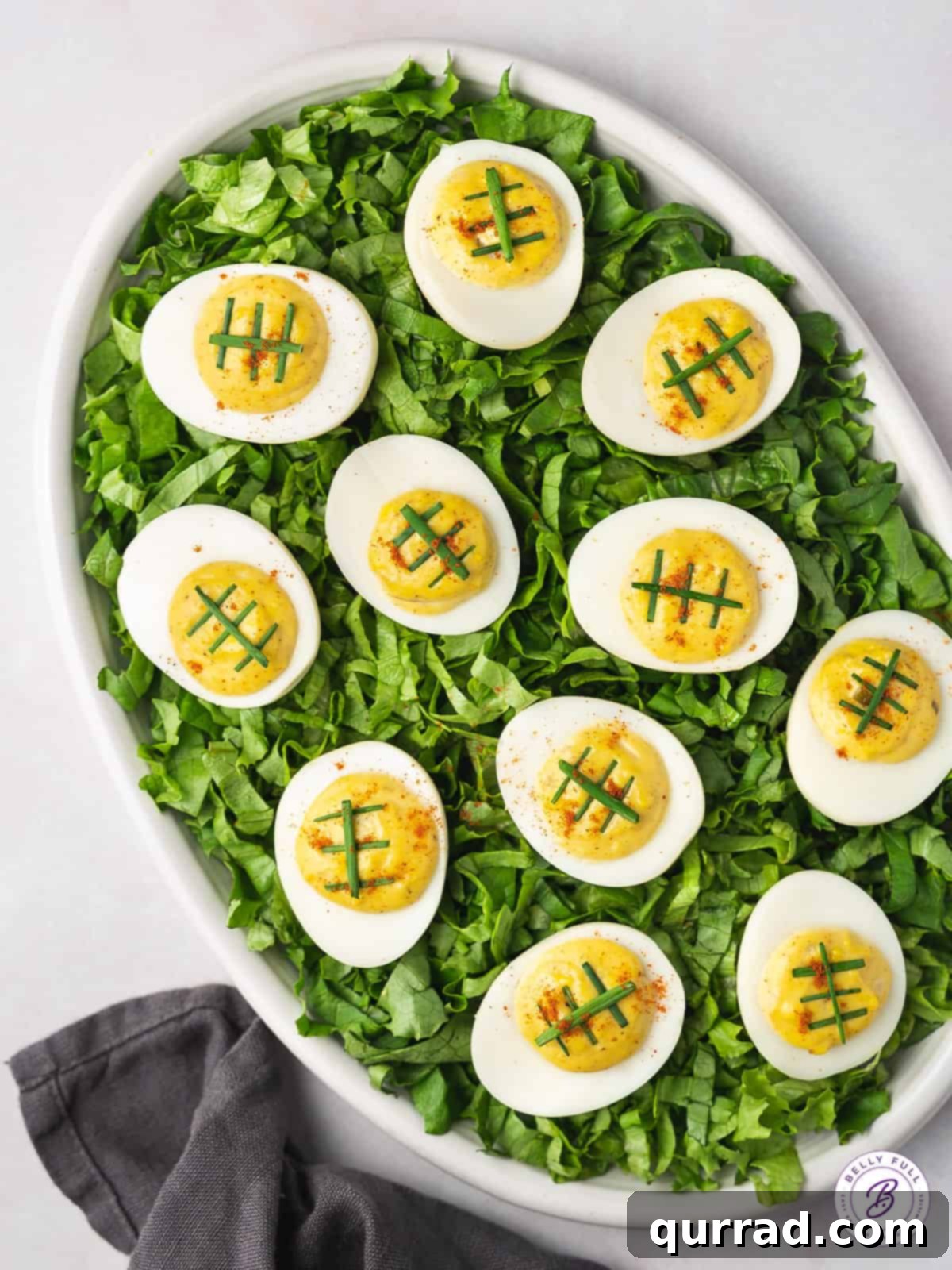 Touchdown Deviled Eggs 2 deviled eggs garnished with scallions as "football laces" on bed of shredded romaine lettuce
