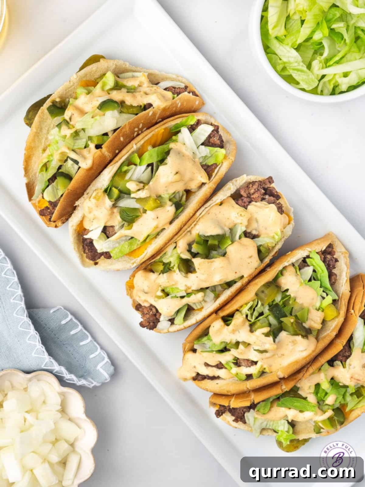 A mouthwatering arrangement of Big Mac Tacos, highlighting their vibrant ingredients and delicious appeal. An inviting overhead shot of several Big Mac Tacos arranged neatly on a pristine white platter, showcasing all their delicious toppings.