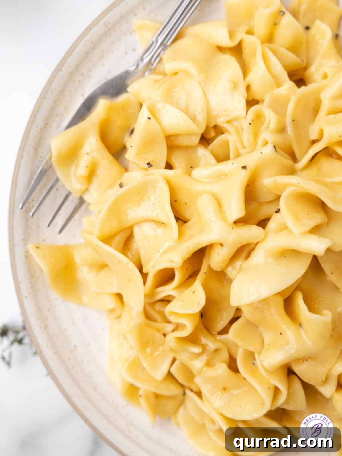Cafeteria Noodles are a popular side dish made with egg noodles, cream of chicken soup, broth, and butter. Ready in 20 minutes! A close-up view of a plate of buttered egg noodles, ready to be served