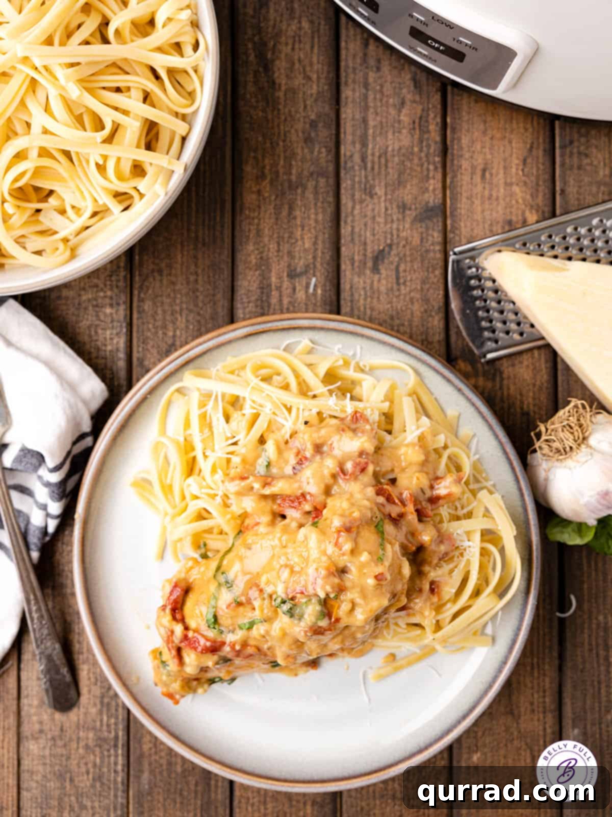 This Crockpot Marry Me Chicken features tender, juicy chicken breasts in a rich, creamy sauce with sundried tomatoes and parmesan. Creamy sundried tomato chicken over pasta on a plate