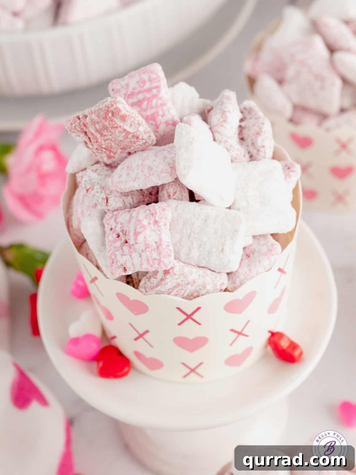 Pink and white muddy buddies elegantly arranged in a Valentine's decorated cup, ready for a special treat.