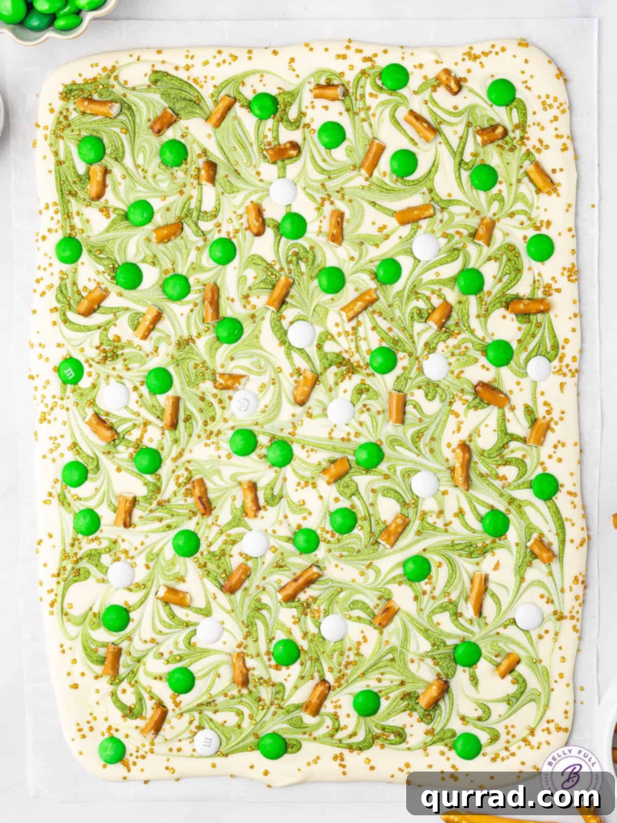 Overhead view of an uncut slab of vibrant green and white marbled chocolate bark before breaking, showcasing the festive swirl design