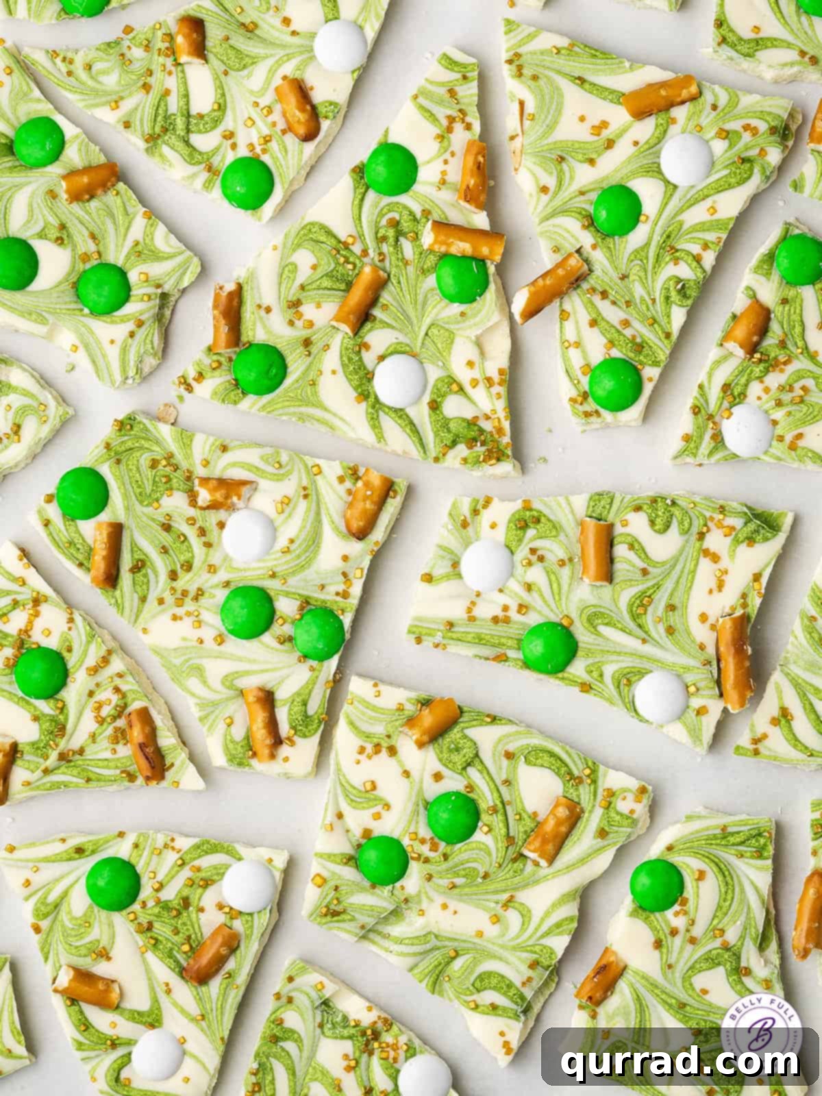 Broken pieces of white and green St. Patrick's Day chocolate bark arranged on a surface, highlighting the marble effect and toppings