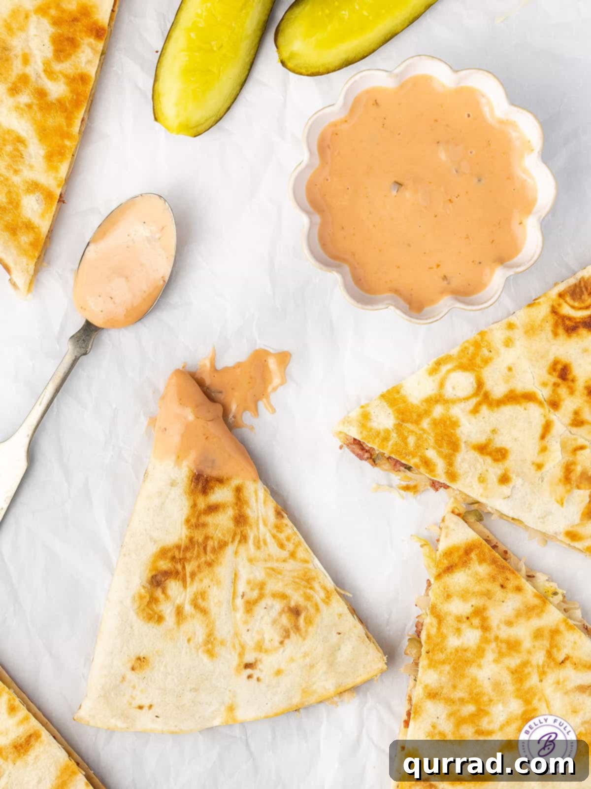 Reuben Quesadillas are loaded with corned beef, sauerkraut, Swiss cheese, and Thousand Island Dressing. Easy recipe for leftover corned beef! Overhead view of pieces of a Reuben quesadilla with a little dish of thousand island dressing